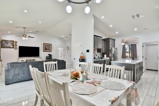 dining space with light wood-type flooring, ceiling fan, lofted ceiling, and sink