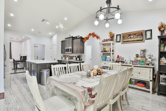 dining space with a chandelier, light hardwood / wood-style floors, and vaulted ceiling