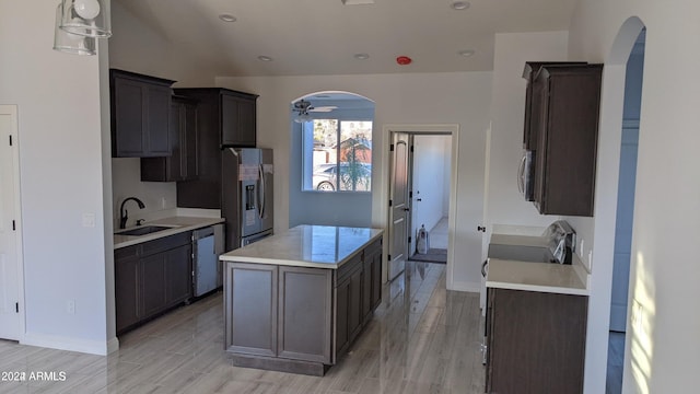 kitchen with a kitchen island, sink, light wood-type flooring, and stainless steel appliances