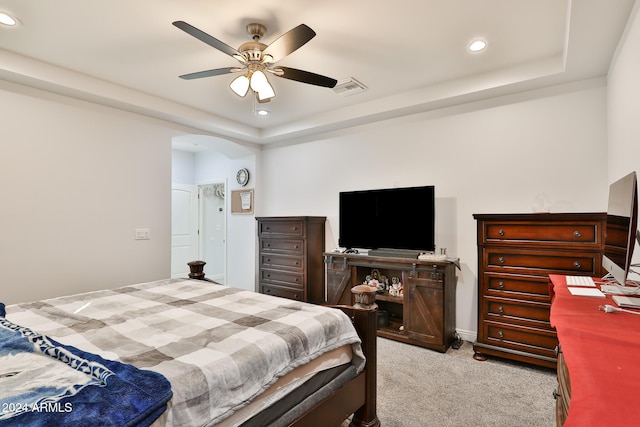 carpeted bedroom with a raised ceiling and ceiling fan