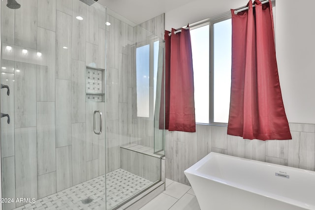 bathroom with separate shower and tub, tile patterned floors, and tile walls