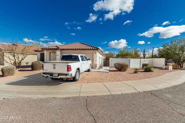 view of front of property with a fenced front yard, a garage, a tile roof, concrete driveway, and stucco siding