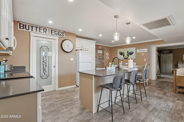 5154 N 83rd St, Scottsdale, AZ 85250 - kitchen with freestanding refrigerator, light wood finished floors, white cabinets, dark countertops, and a breakfast bar area