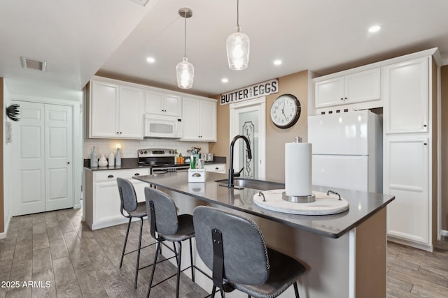 5154 N 83rd St, Scottsdale, AZ 85250 - kitchen featuring white appliances, a sink, dark countertops, a kitchen breakfast bar, and recessed lighting