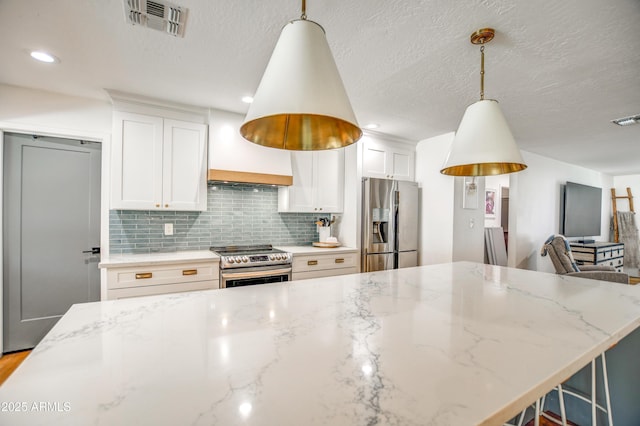 kitchen with stainless steel appliances, white cabinetry, light stone countertops, and pendant lighting