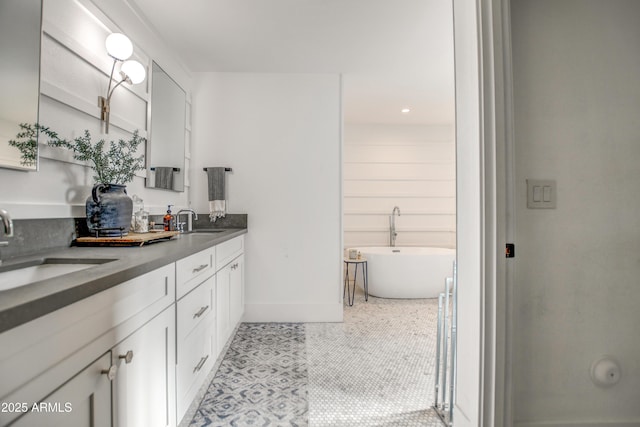 bathroom with tile patterned floors, vanity, and a washtub