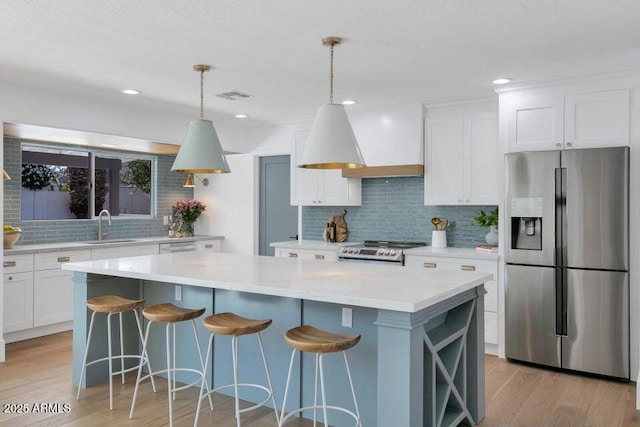 kitchen featuring stainless steel refrigerator with ice dispenser, range, white cabinets, and backsplash