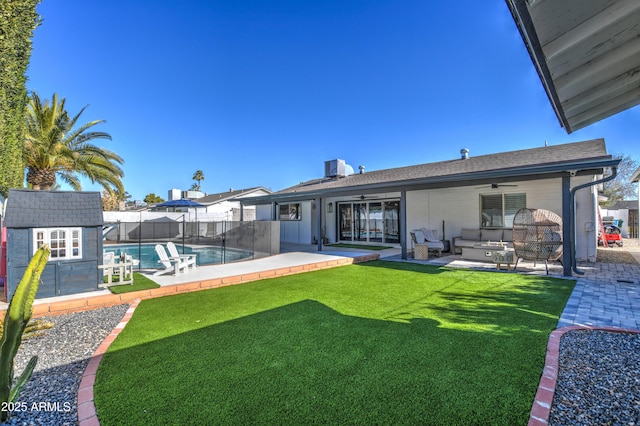 back of house featuring a patio area, outdoor lounge area, ceiling fan, a storage unit, and a fenced in pool