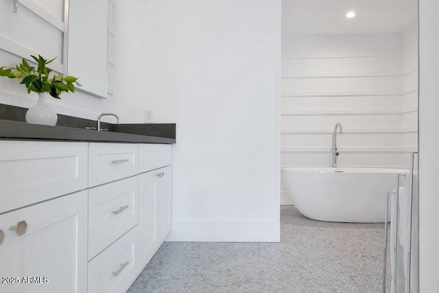 bathroom featuring tile patterned floors, vanity, and a washtub