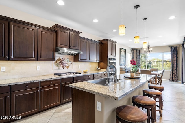 31156 N 137th Ln, Peoria, AZ 85383 - kitchen featuring a sink, under cabinet range hood, light tile patterned floors, stainless steel gas stovetop, and a breakfast bar