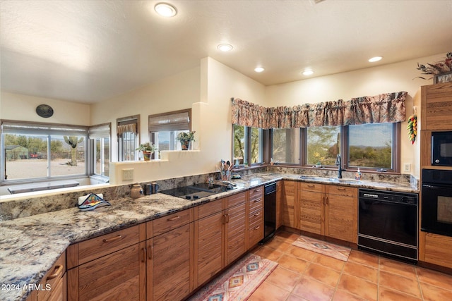 kitchen with light stone countertops, sink, light tile patterned flooring, and black appliances