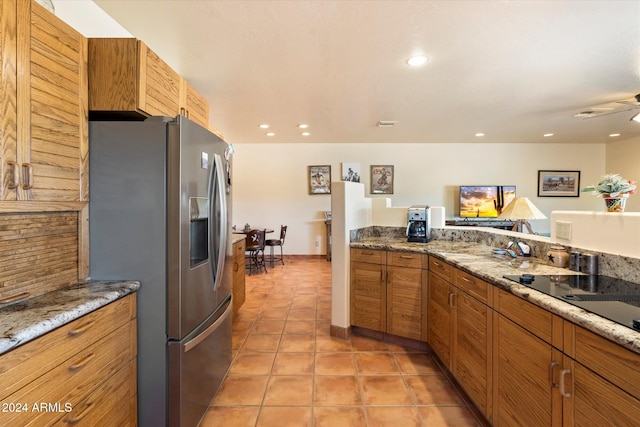 kitchen with light stone countertops, stainless steel fridge, light tile patterned floors, and ceiling fan