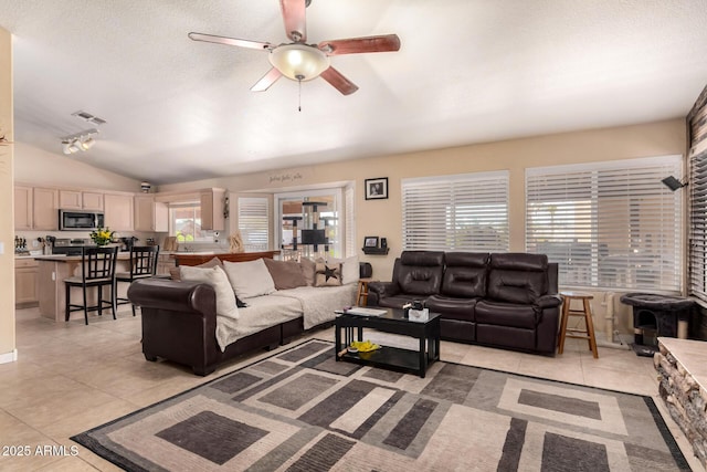 living area with light tile patterned floors, ceiling fan, a textured ceiling, lofted ceiling, and visible vents