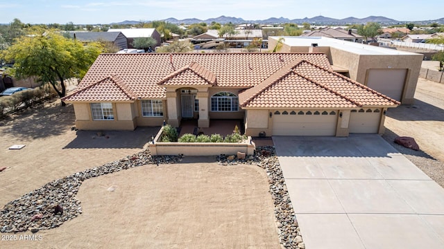 mediterranean / spanish home featuring driveway, an attached garage, a mountain view, and stucco siding