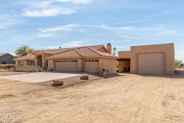 view of front facade with driveway, a chimney, a tile roof, and stucco siding