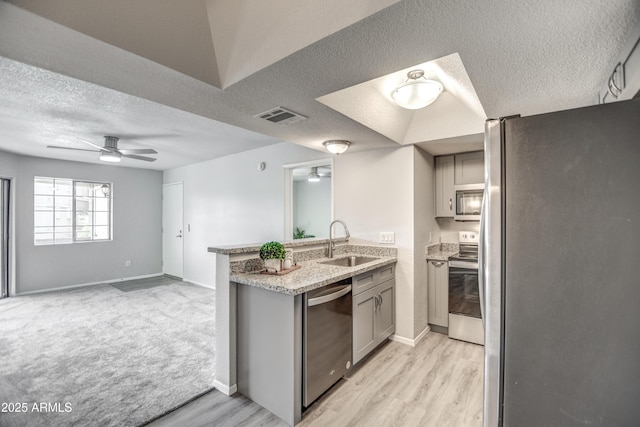 kitchen with sink, gray cabinetry, a textured ceiling, appliances with stainless steel finishes, and kitchen peninsula