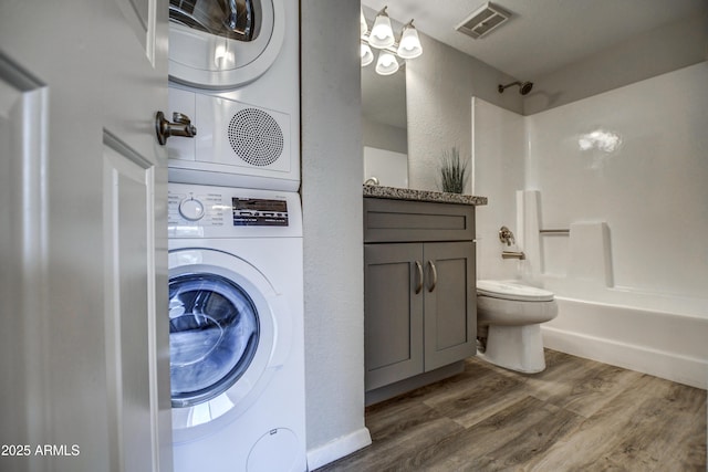 clothes washing area featuring stacked washer and clothes dryer and dark hardwood / wood-style floors