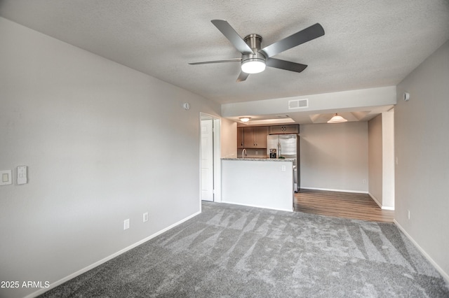 unfurnished living room with dark colored carpet, ceiling fan, and a textured ceiling