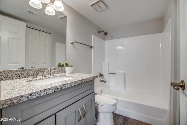 full bathroom with vanity, hardwood / wood-style floors, shower / bathtub combination, and toilet