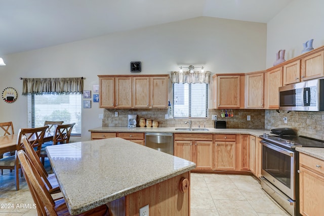 kitchen with appliances with stainless steel finishes, tasteful backsplash, a healthy amount of sunlight, and a center island