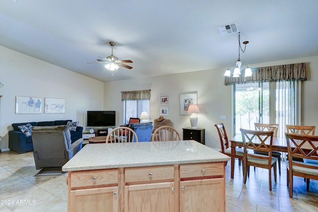 kitchen with pendant lighting, ceiling fan with notable chandelier, a healthy amount of sunlight, and a kitchen island