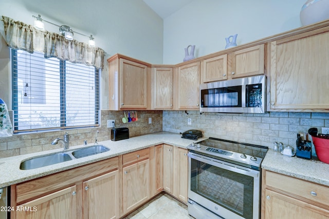 kitchen with a wealth of natural light, appliances with stainless steel finishes, sink, and decorative backsplash