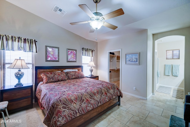 tiled bedroom featuring lofted ceiling, ceiling fan, a closet, and a walk in closet