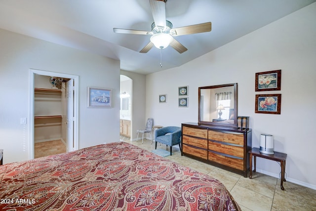 bedroom with a closet, a spacious closet, ensuite bath, light tile patterned floors, and ceiling fan