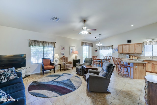 tiled living room featuring ceiling fan with notable chandelier, plenty of natural light, and vaulted ceiling