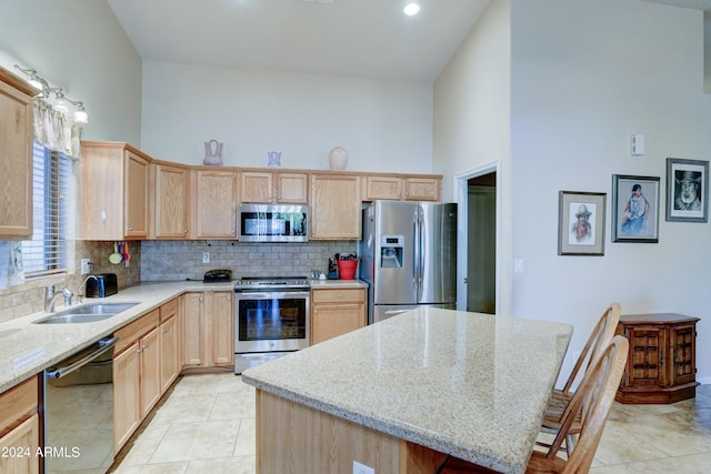 kitchen with appliances with stainless steel finishes, sink, light stone counters, and a center island