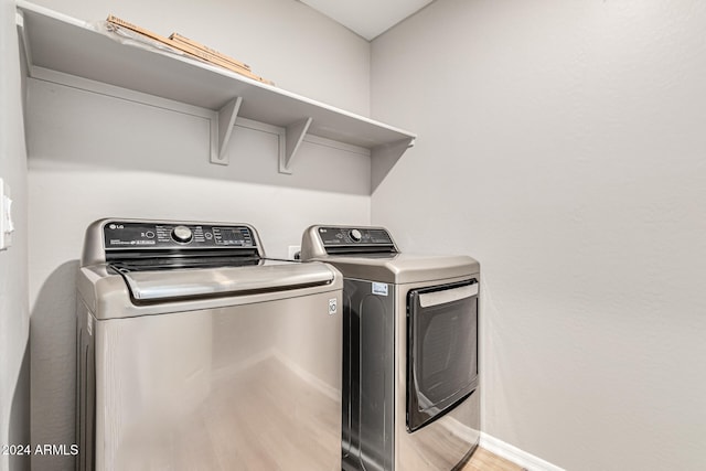 laundry area with washer and clothes dryer and light hardwood / wood-style floors