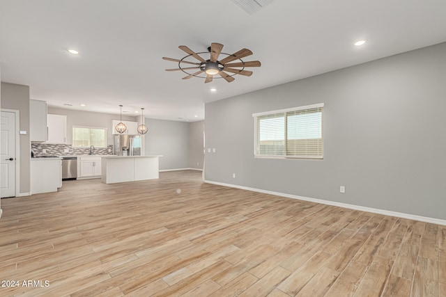 unfurnished living room featuring ceiling fan, sink, and light hardwood / wood-style flooring