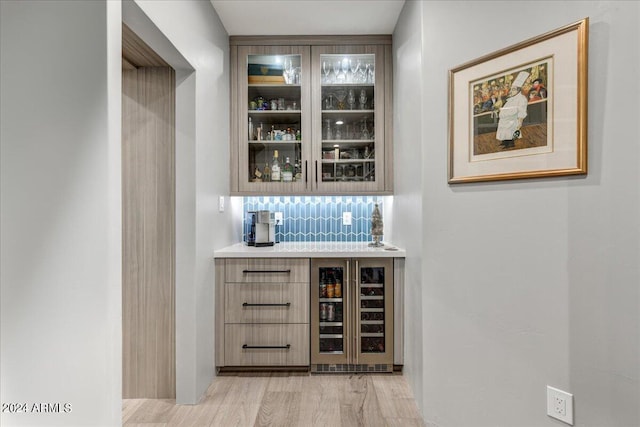 bar with wine cooler, light hardwood / wood-style floors, and tasteful backsplash