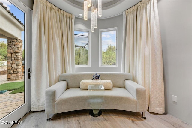 sitting room featuring a tray ceiling, hardwood / wood-style flooring, and an inviting chandelier