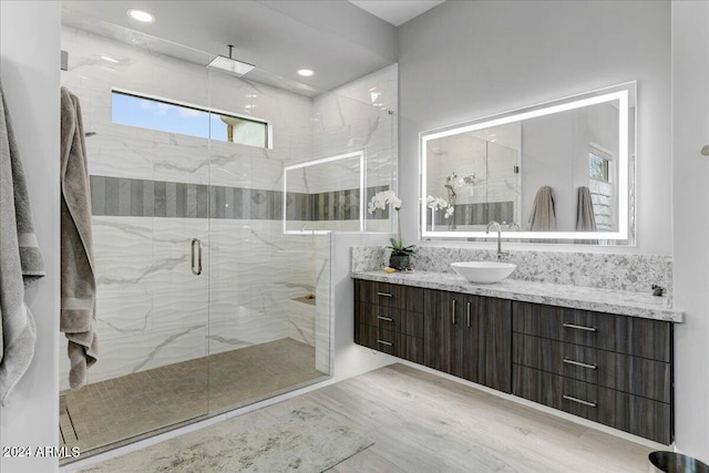 bathroom featuring wood-type flooring, an enclosed shower, plenty of natural light, and oversized vanity