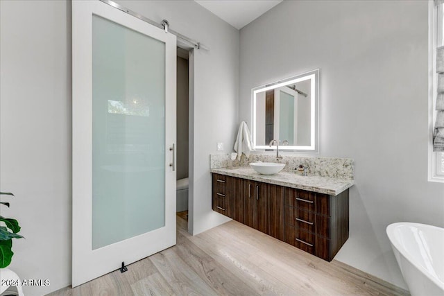 bathroom featuring toilet, a bath, vanity, and hardwood / wood-style flooring