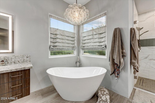 bathroom with a notable chandelier, a wealth of natural light, vanity, and a bathtub