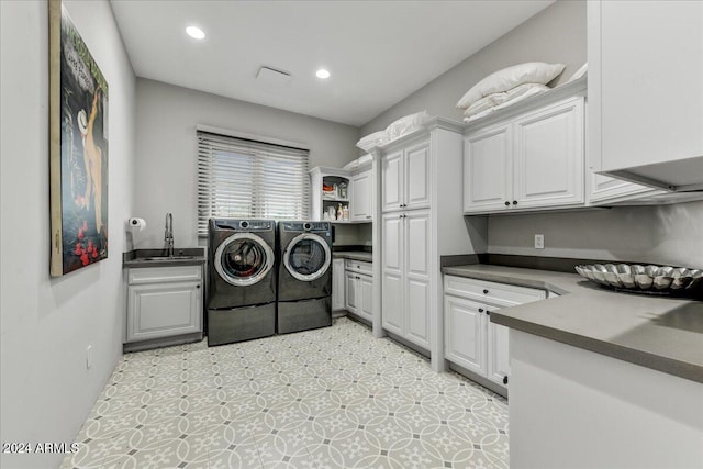 washroom featuring washing machine and dryer, sink, cabinets, and light tile floors