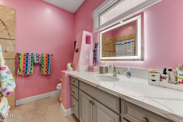 bathroom featuring tile floors, toilet, and vanity with extensive cabinet space