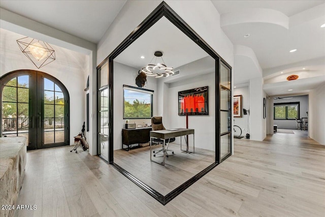 foyer with a chandelier, light hardwood / wood-style flooring, and french doors