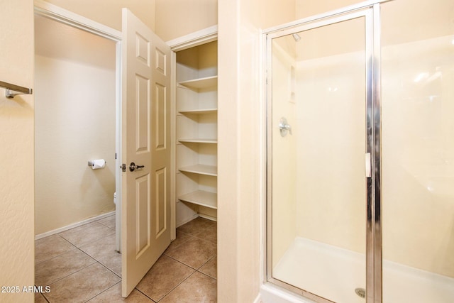 full bath with a shower stall, toilet, and tile patterned floors