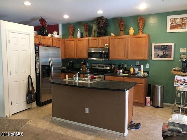 kitchen featuring light tile patterned flooring, a sink, stainless steel appliances, dark countertops, and brown cabinets
