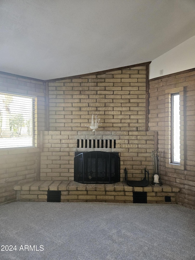 unfurnished living room featuring carpet, plenty of natural light, brick wall, and vaulted ceiling