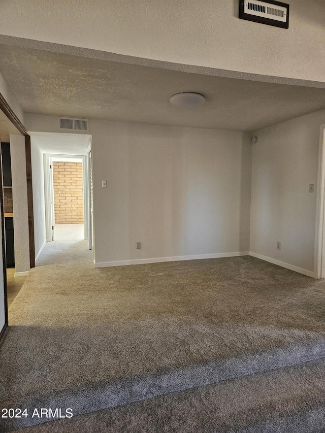 carpeted empty room with a textured ceiling