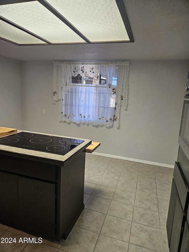 kitchen with black electric cooktop, light tile patterned flooring, and oven