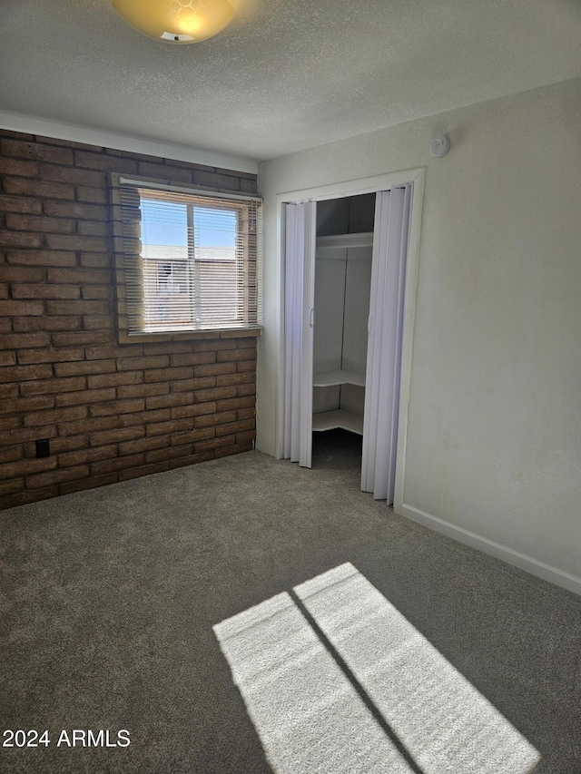 unfurnished bedroom with dark colored carpet, a textured ceiling, and a closet