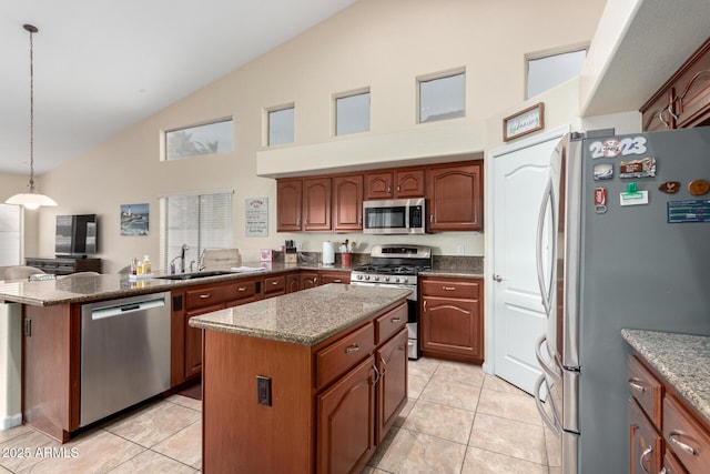 kitchen featuring sink, stone counters, appliances with stainless steel finishes, a center island, and decorative light fixtures