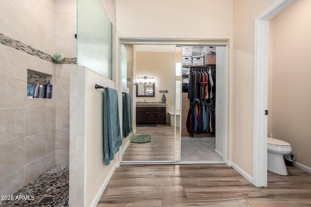 bathroom featuring tiled shower, vanity, toilet, and hardwood / wood-style floors