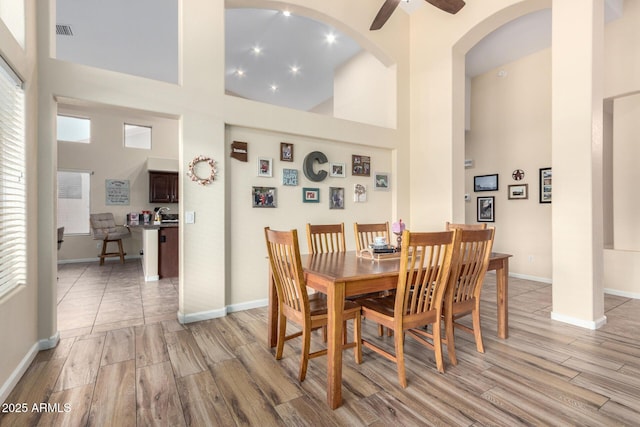 dining area with a high ceiling, ceiling fan, and light hardwood / wood-style floors