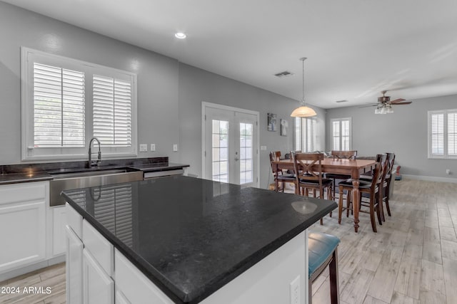 kitchen with light hardwood / wood-style flooring, a kitchen island, sink, ceiling fan, and white cabinets